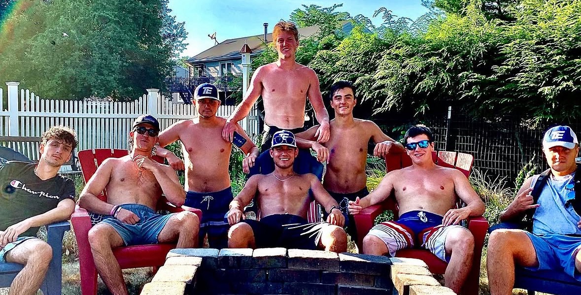 Matthew Tenney and his crew gathered around a fire pit, several wearing TE hats