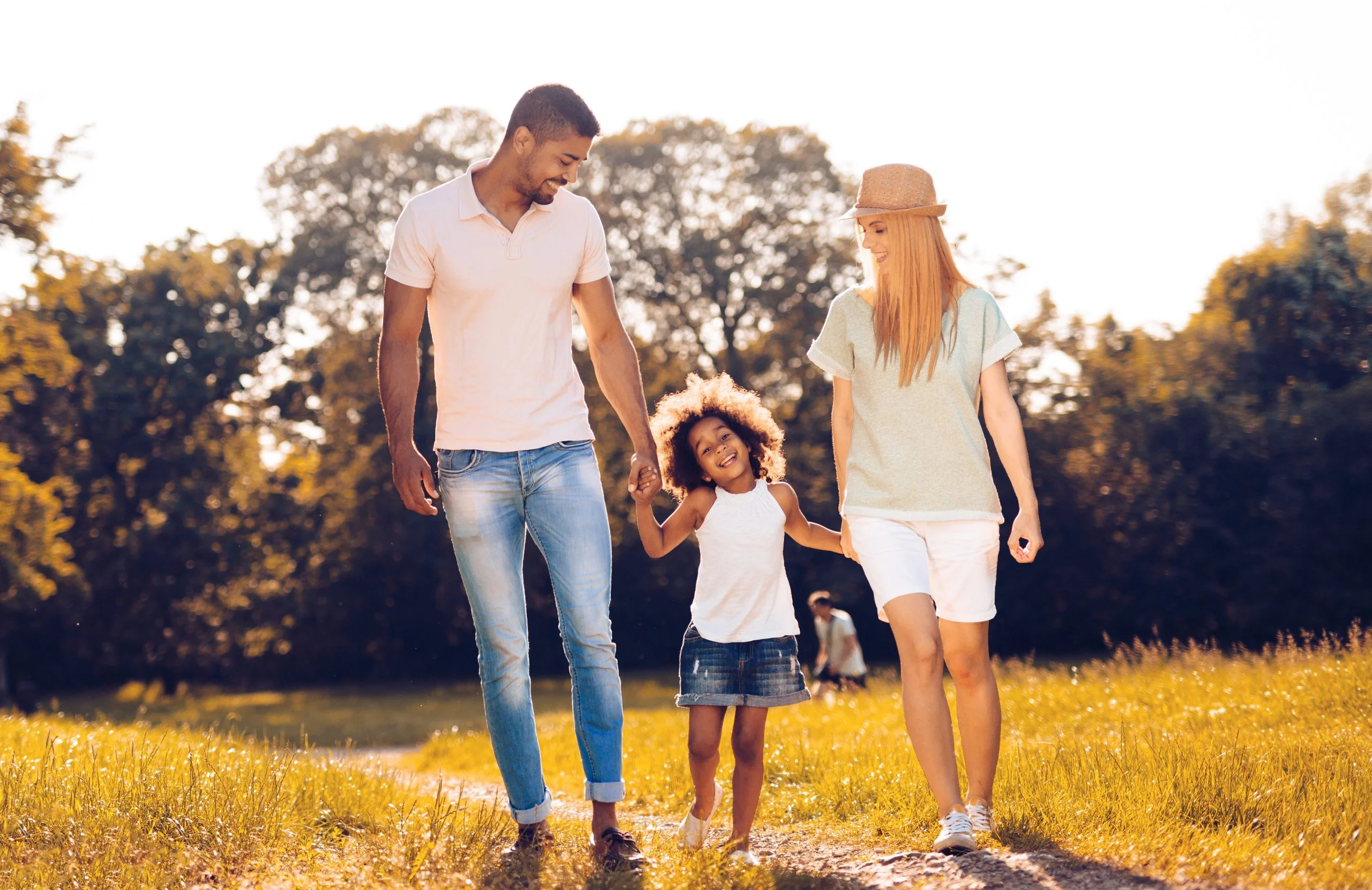 A happy family walking together through a sunny field, holding hands
