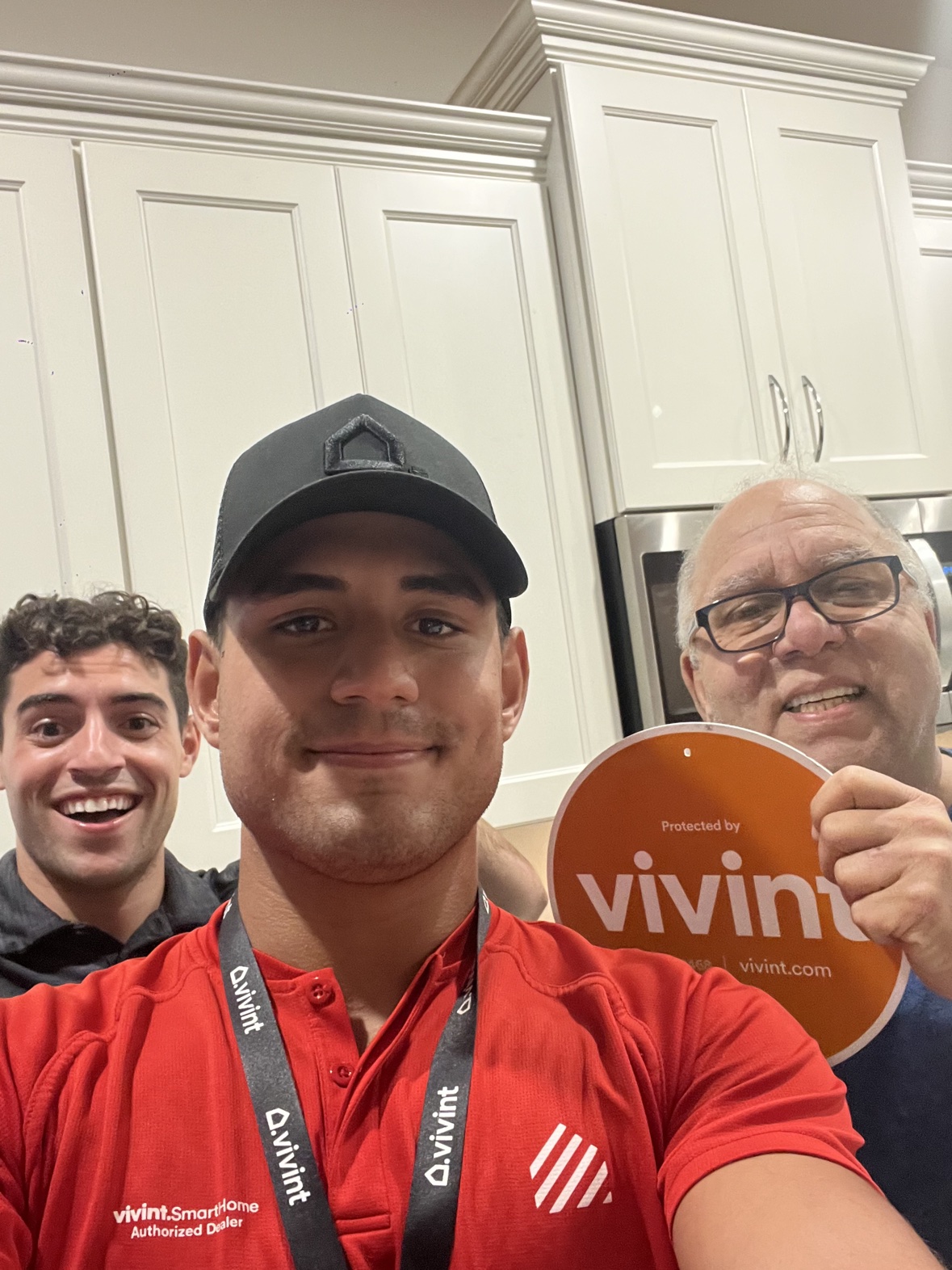 Kitchen selfie of Matthew in his red Vivint polo with a customer holding the sign