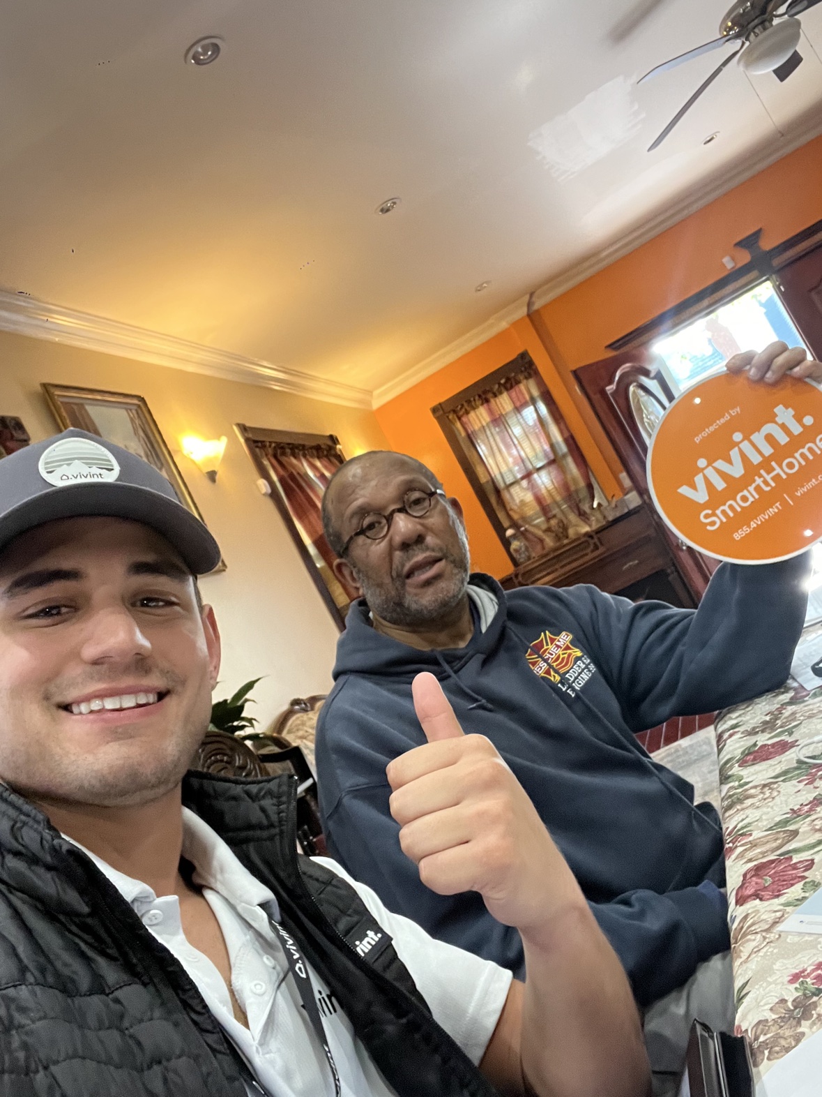 Selfie at a customer kitchen table, the Vivint sign held high