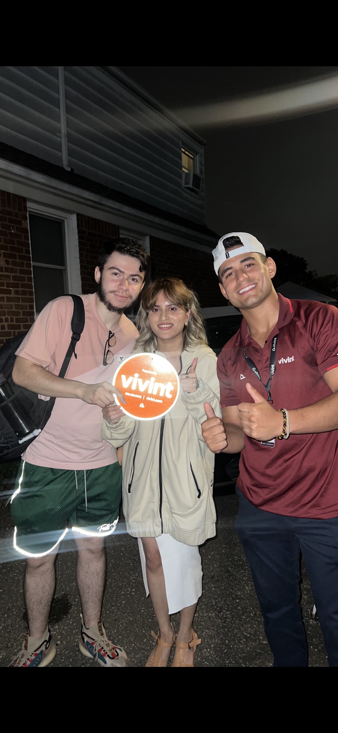 Night photo outside a house with a young couple holding the Vivint sign
