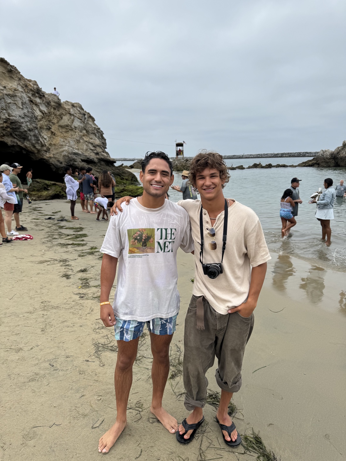 Matthew on the beach right after his baptism in a wet shirt, smiling with a friend