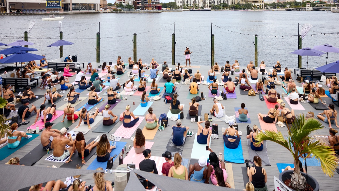 A huge crowd on yoga mats at a waterfront deck event in Tampa