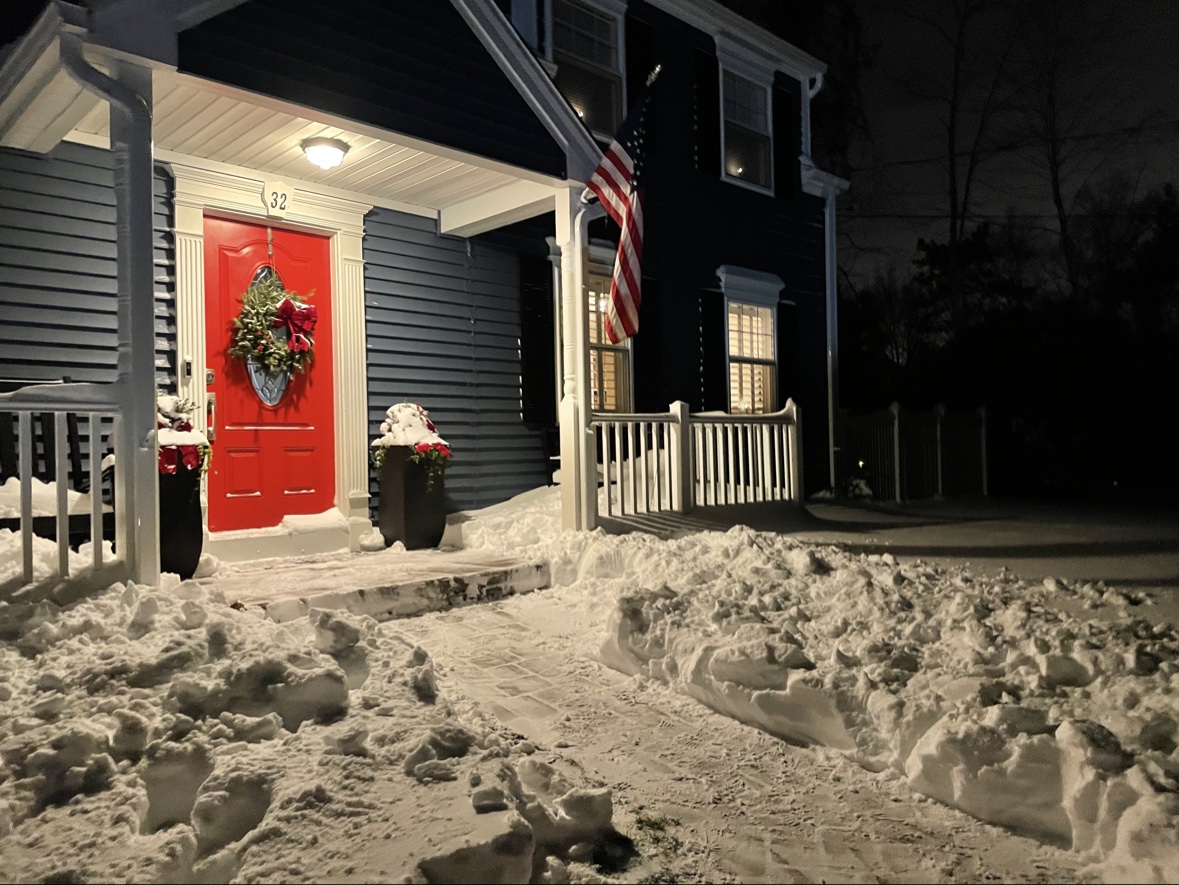 Snow covered house with a red door at night