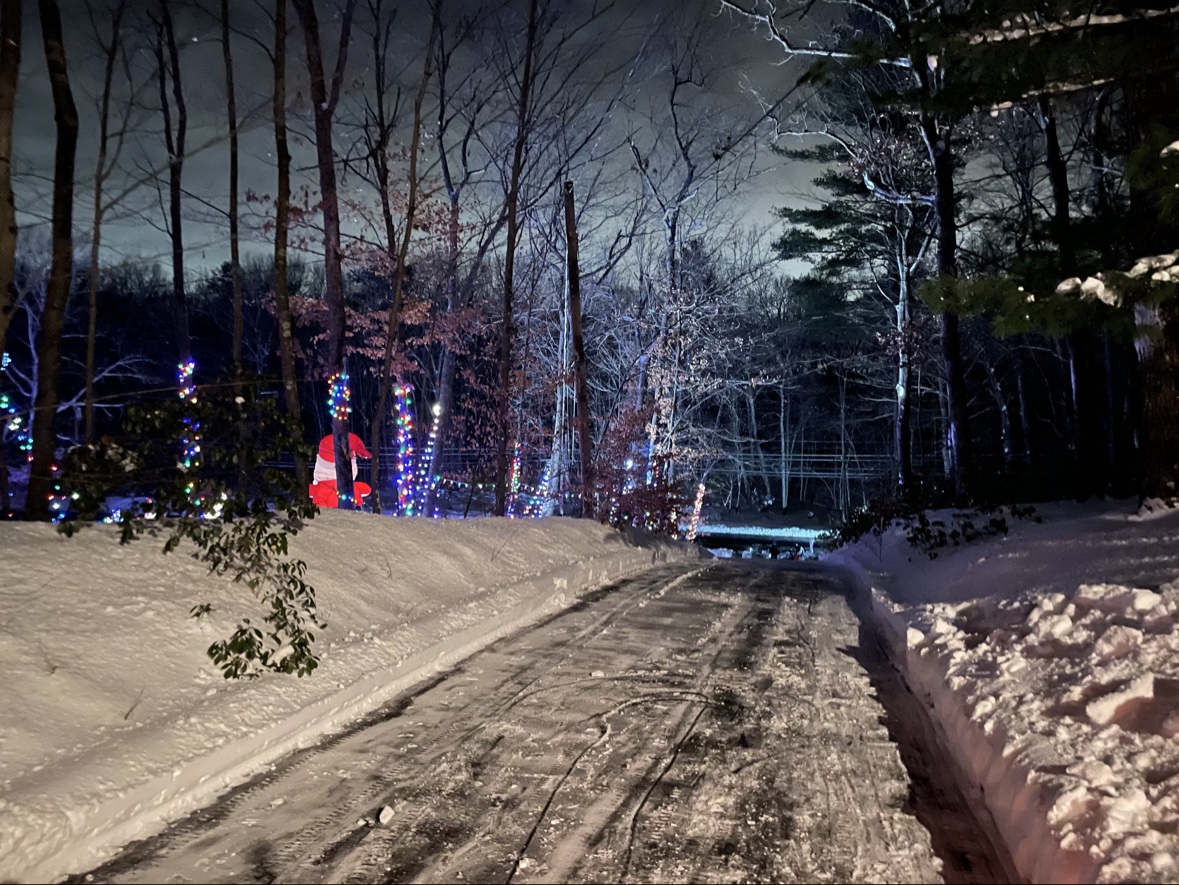 Snow covered driveway at night with lights on