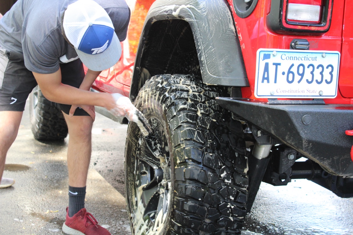 Matthew scrubbing a Jeep tire while detailing