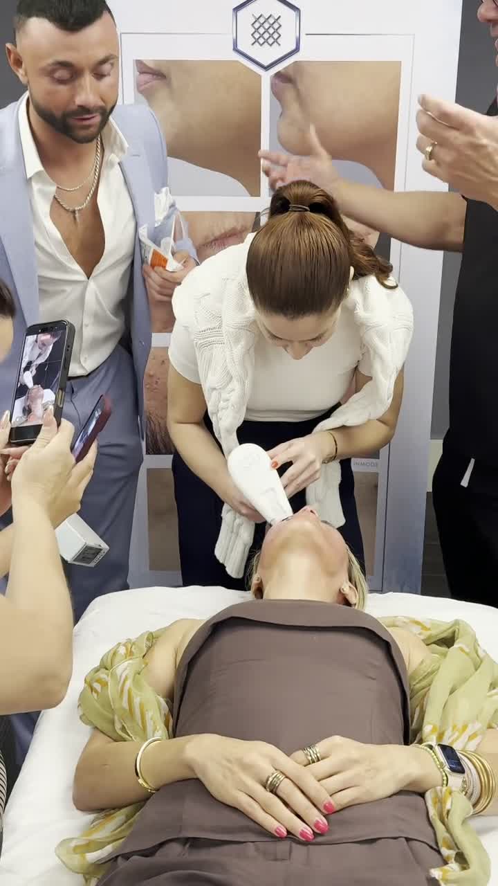 Morpheus8 treatment in progress, Matthew Tenney trackside in a light blue blazer holding product while attendees film